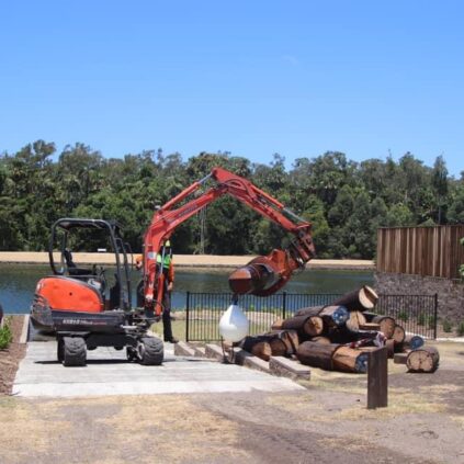 Tree Service using excavator to retrieve logs they floated down river from bridge restoration project in Sunshine Cove, Maroochydore. Waterfront tree removal access.